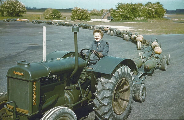WAAF tractor driver. A WAAF tractor driver with a train of full bomb trolleys